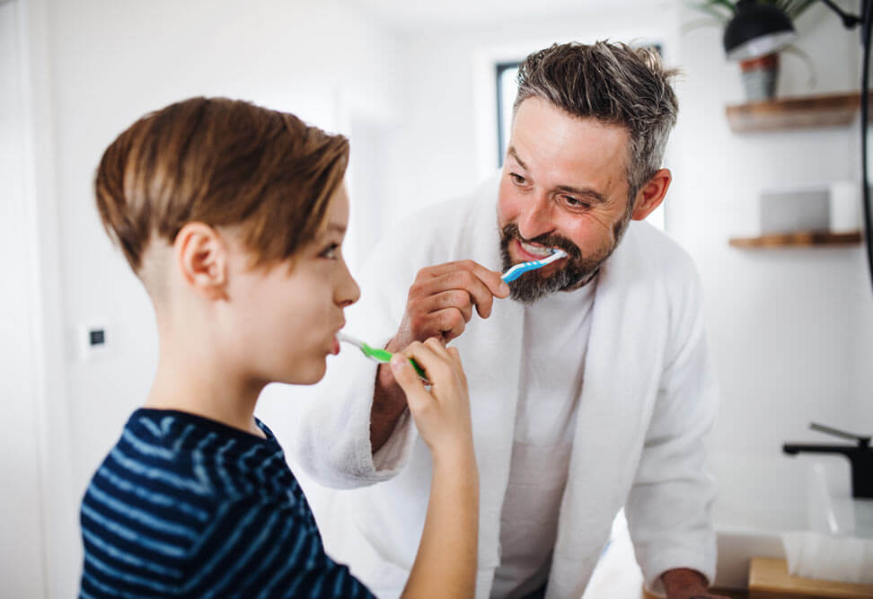 Mature father with small son brushing teeth.